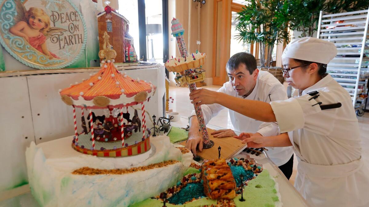 Jeff Lehuede, left, head pastry chef for the Resort at Pelican Hill, is assisted Monday by pastry cook Tam Nguyen as they assemble the resort's annual gingerbread village in the main lobby.