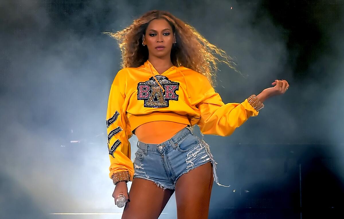 Beyoncé in a yellow shirt and cutoff shorts, with swirling smoke behind her.