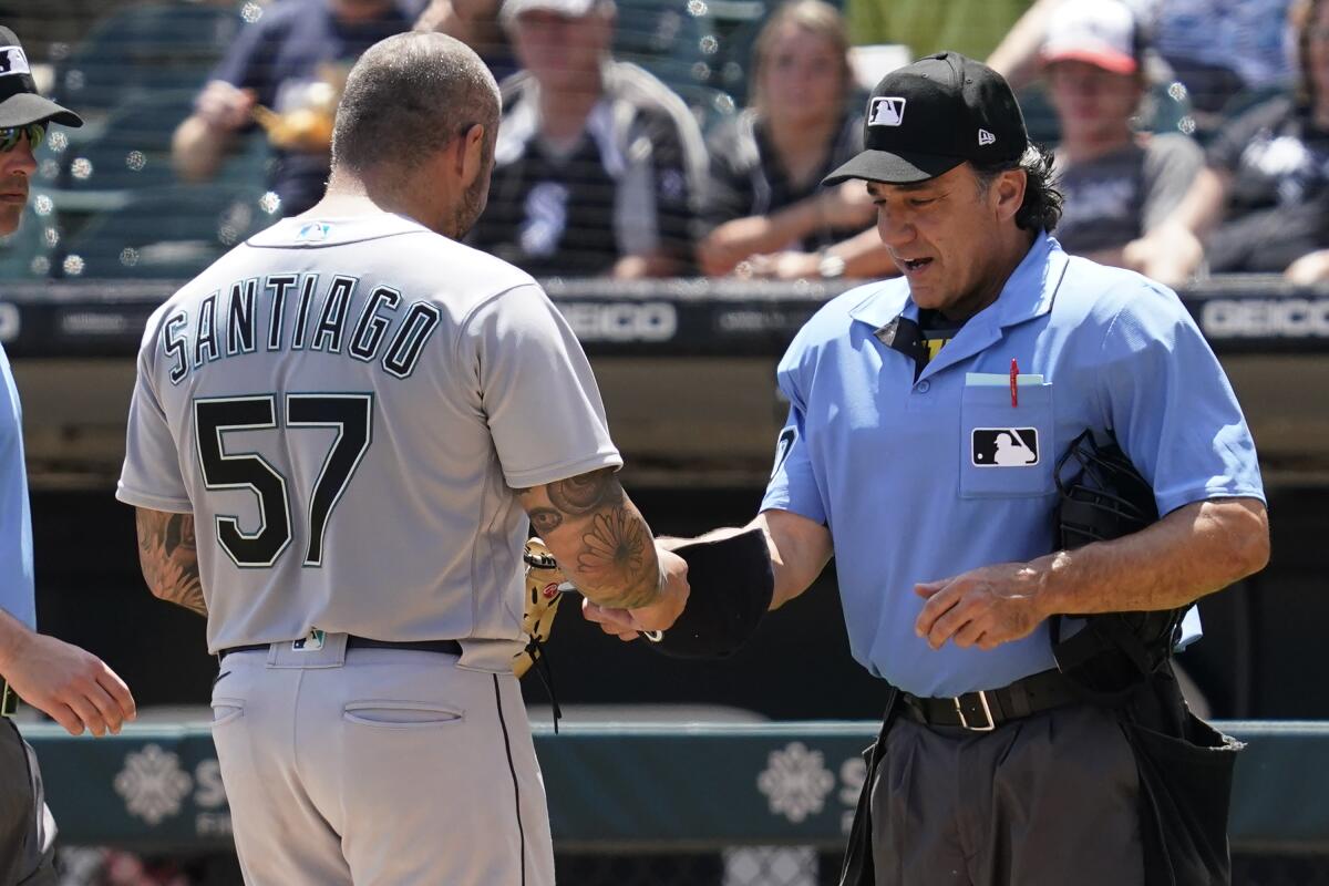 Home Plate umpire Phil Cuzzi, right, talks with Seattle Mariners relief pitcher Hector Santiago during the fifth inning in the first baseball game of a doubleheader against the Chicago White Sox in Chicago, Sunday, June 27, 2021. Santiago was ejected by Cuzzi. (AP Photo/Nam Y. Huh)