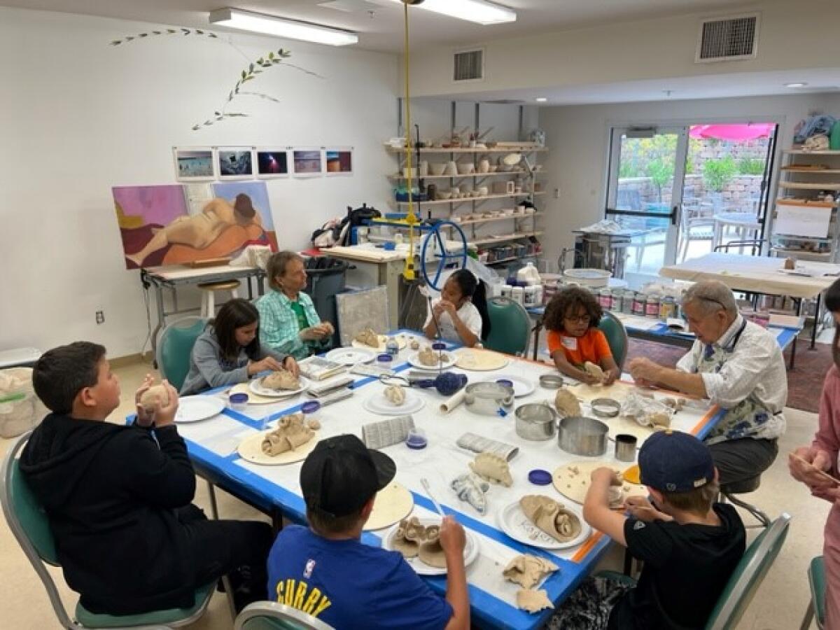 Residents Judy McNeely, John Urabec and Elizabeth Russell lead a ceramics activity for participating children at White Sands.