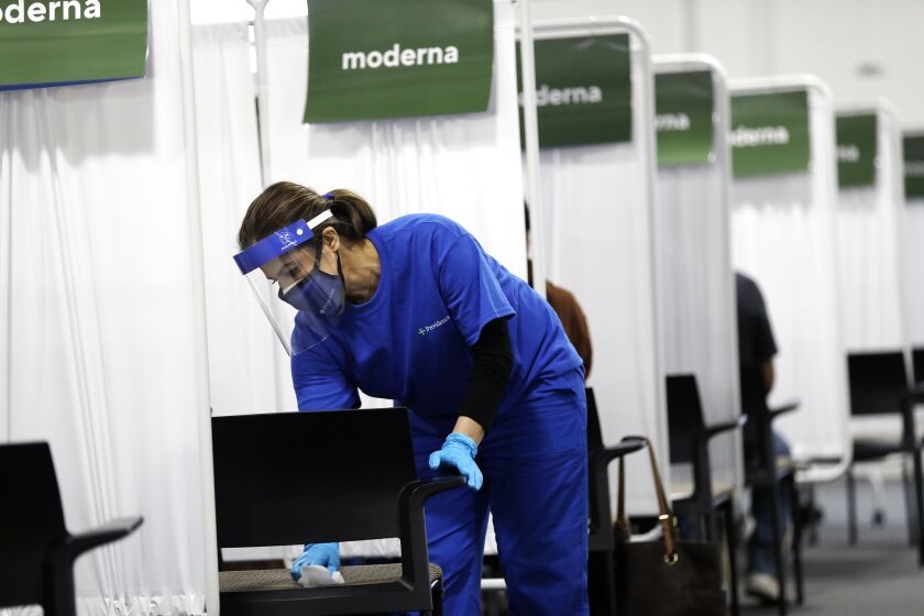 SANTA ANA-CA-APRIL 22, 2021: Registered nurse Paria Nadjafi cleans a chair between patients at a new mass vaccination site in Orange County-the Providence Vaccine Clinic at Edwards Lifescience in Santa Ana on Thursday, April 22, 2021. (Christina House / Los Angeles Times)