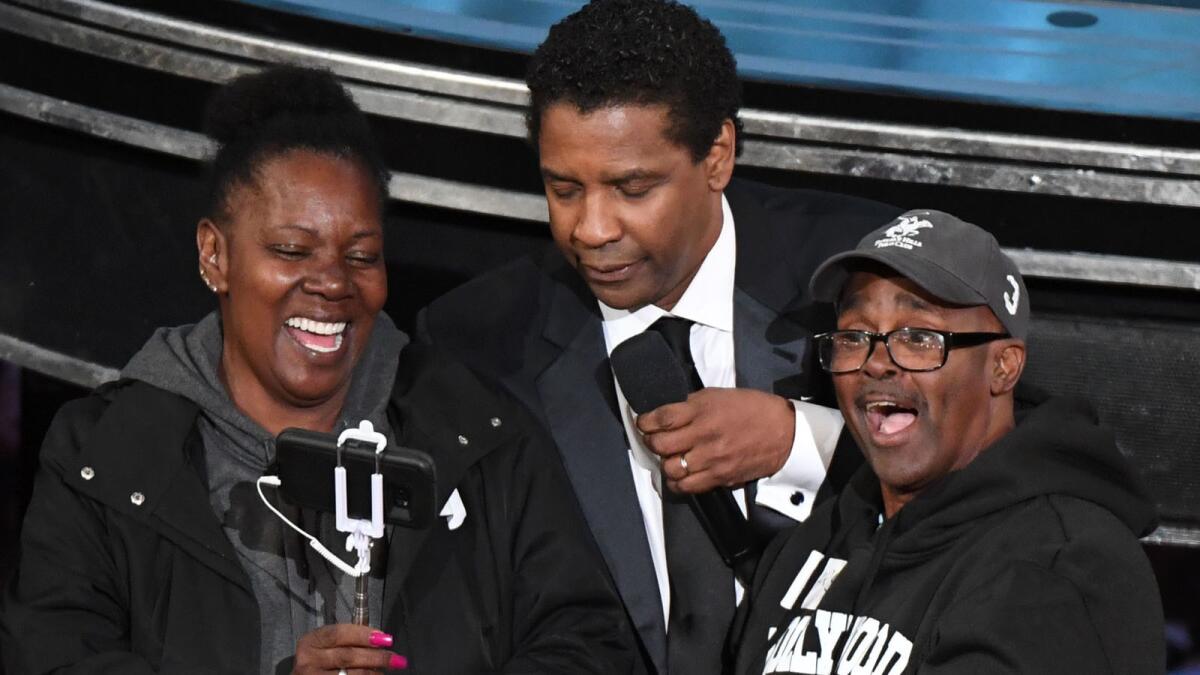 Actor Denzel Washington, center, greets tourists Gary Alan Coe, aka "Gary From Chicago," and his fiancée, Vickie Vines, at the Academy Awards on Sunday. Coe had recently been released from prison.