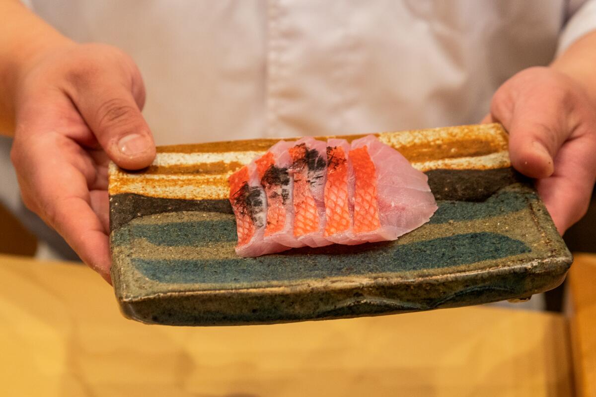 CITY OF INDUSTRY, CA - WEDNESDAY, APRIL 26, 2023 - Close up of Chef/Owner Ryan Kwak displaying a Kinmedai sashimi (Golden Eye Snapper) seared with Japanese charcoal at Sushi Yeun omakase restaurant in the City of Industry, April 26, 2023. (Ricardo DeAratanha/Los Angeles Times)