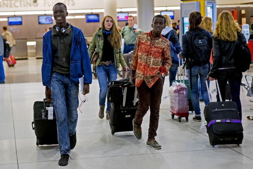 Johnson Nellon, left, and his brother Thomas Nellon smile at their mother as they arrive from Liberia at John F. Kennedy International Airport.