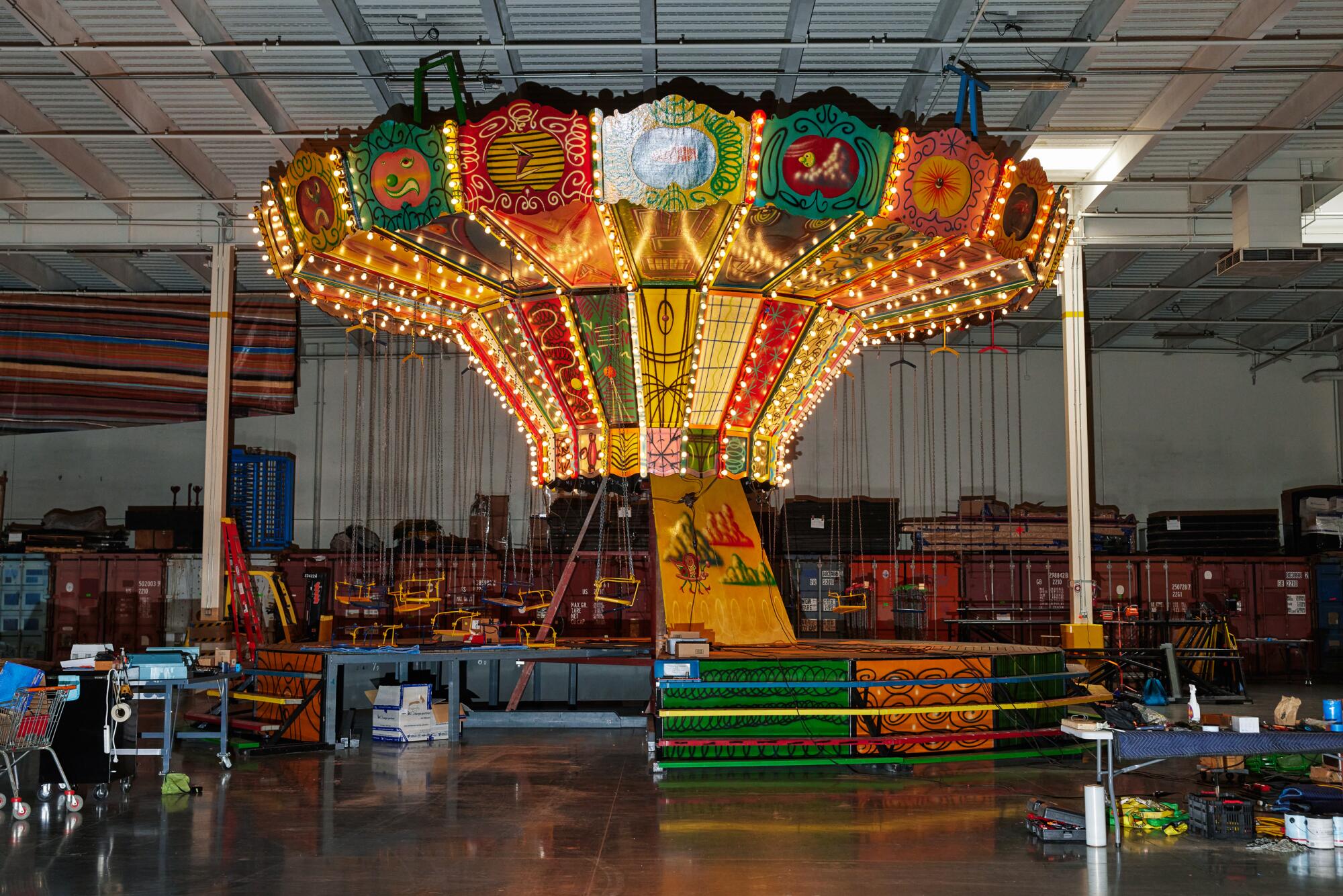 A Kenny Scharf-designed swing ride is partly lighted in a Los Angeles warehouse. 