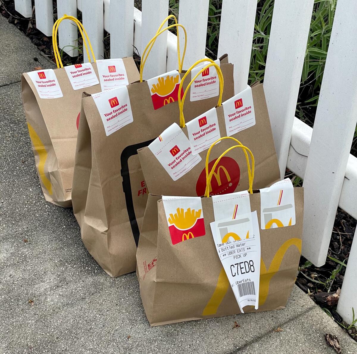 Several bags from McDonald's sit on a sidewalk.