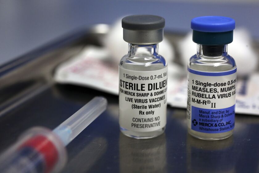 A vial containing the MMR vaccine, right, and another vial containing the diluent used to mix the vaccine, sit on a tray before being loaded into a syringe at the Medical Arts Pediatric Med Group on Wilshire Bouelvard in Los Angeles.