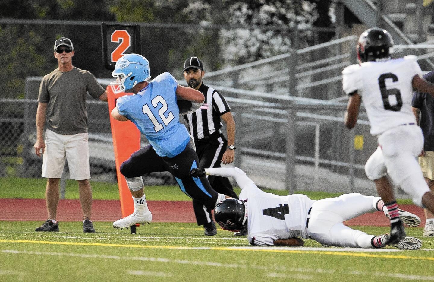 Corona del Mar High's Peter Bush breaks free of a tackle from Palos Verdes' Giorgio Henderson during the season opener at Jim Scott Stadium on Friday. Bush scored a touchdown on the play.