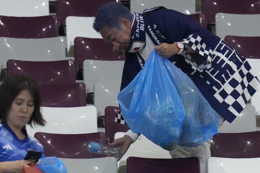 Hinchas de Japón limpian las gradas al final del juego del Grupo E entre Alemania y Japón, en el estadio Jalifa Internacional, en Doha, Qatar, el 23 de noviembre de 2022. (AP Foto/Eugene Hoshiko)