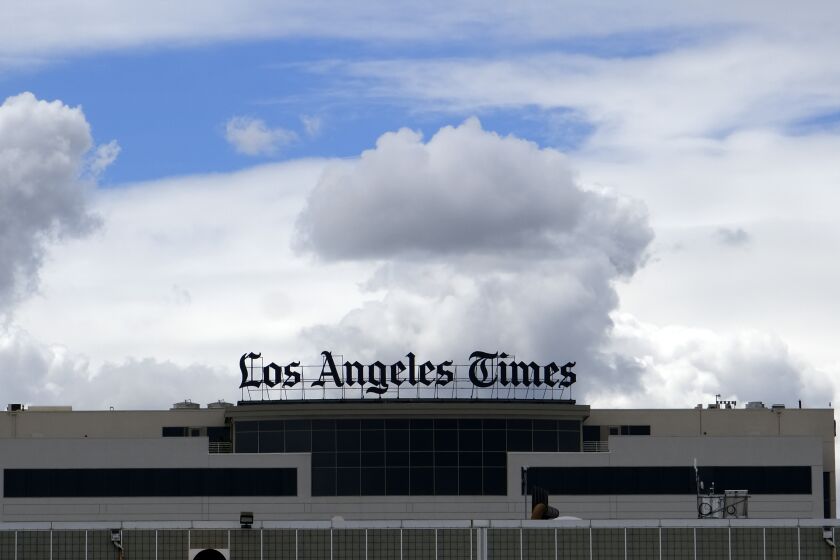 FILE - The Los Angeles Times building is seen behind a fence behind the Los Angeles International Airport, Friday, April 10, 2020. The Los Angeles Times on Wednesday, June 7, 2023, announced plans to cut 74 jobs due to economic challenges as the newspaper strives to transform itself into a digital media organization. (AP Photo/Richard Vogel, File)