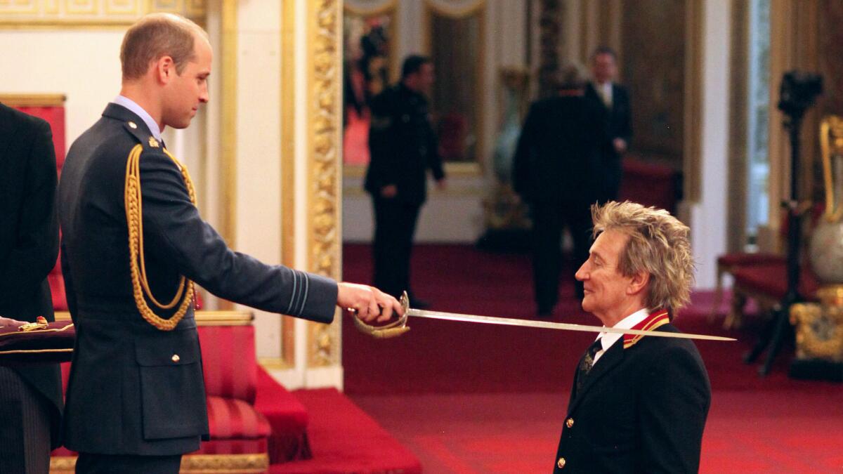 Rod Stewart, right, is made a knight by Prince William in a ceremony Tuesday at Buckingham Palace.