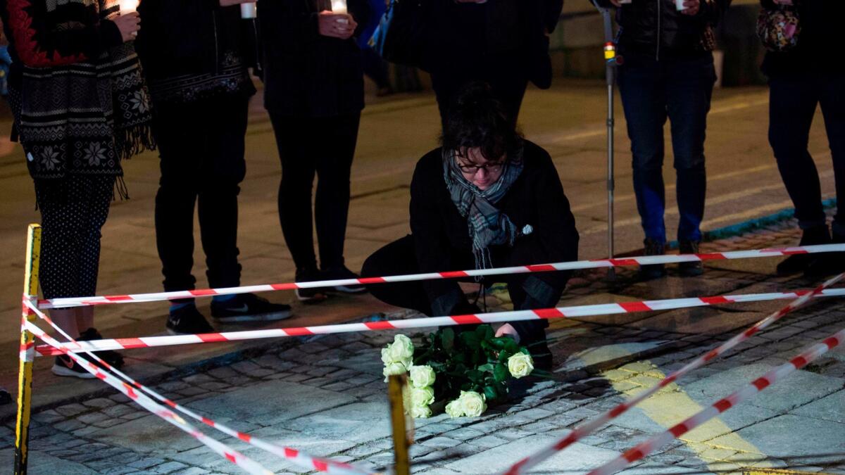 People hold candles while a woman lays flowers during a vigil in front of Warsaw's Palace of Culture, where a man set himself on fire on Oct. 19.