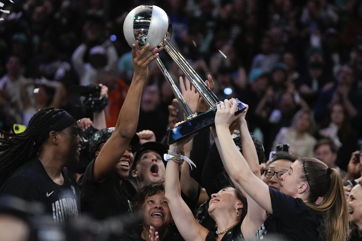 The New York Liberty hold up the WNBA title trophy.