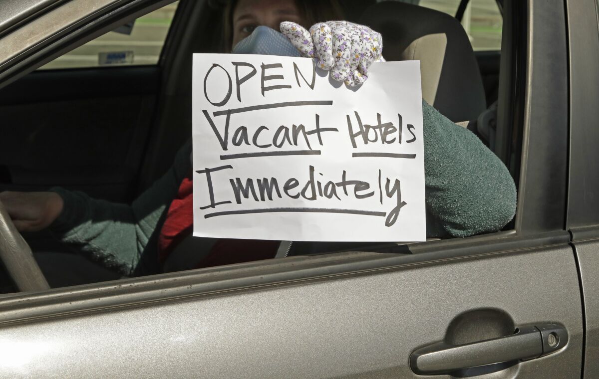 An activist protests from her vehicle outside San Francisco's Moscone Center, asking Mayor London Breed to house homeless people in vacant hotels.