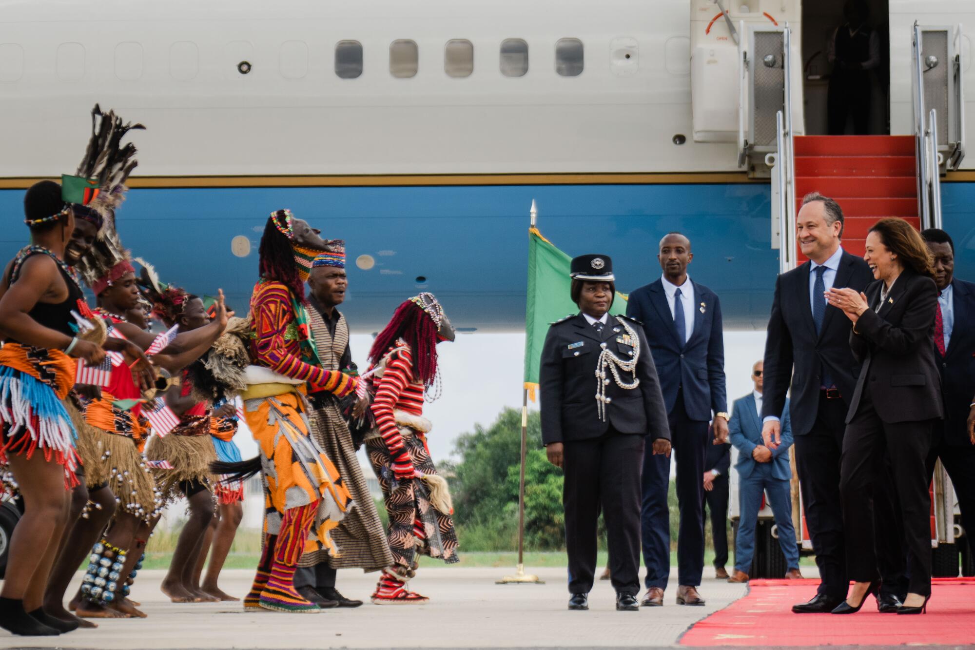 Kamala Harris and her husband, Doug Emhoff, are greeted as they de-plane in Zambia