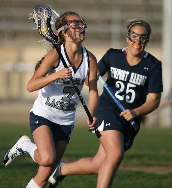 Corona del Mar's Molly Rovzar, left, sprints downfield with the ball as Newport Harbor's Madeline Storch chases after her during the Battle of the Bay lacrosse match at Newport Harbor High School on Friday.