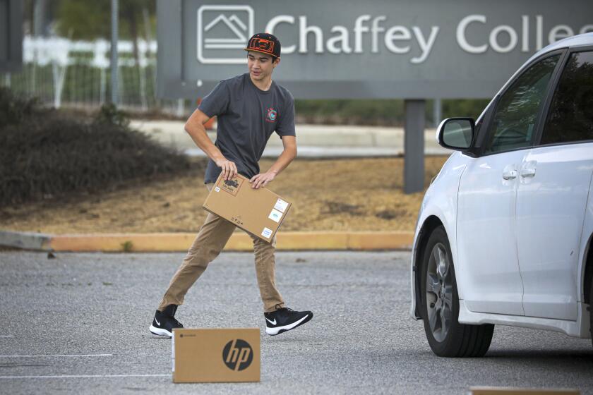 CHINO, CA - MARCH 25, 2020 - Following strict safe distance measures a student picks a laptop placed in the parking lot of Chaffey College on Wednesday, March 25, 2020 at Chino campus. According a press release Chaffey College is loaning about 5,000 laptops to students in need as it transitions most classes online in the wake of the coronavirus outbreak. Chaffey distributed about 1,000 laptops in a drive-thru format at its Rancho Cucamonga campus Tuesday March 24 and Wednesday March 25 at the Chino and Fontana campuses. Staff expect to loan the remaining computers to students in the next few weeks. (Irfan Khan / Los Angeles Times)