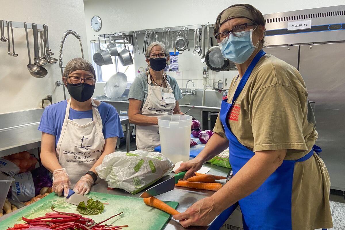 Three people cut up vegetables as part of L.A. Family Housing volunteer services