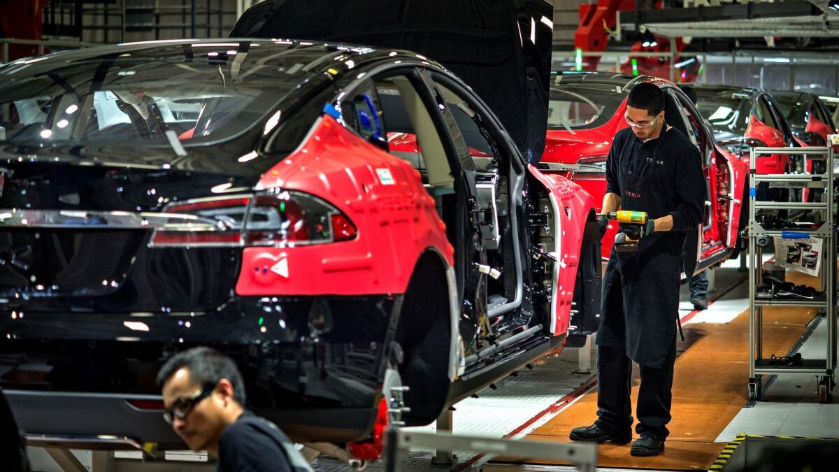 Workers assemble cars at Tesla's factory in Fremont, Calif.