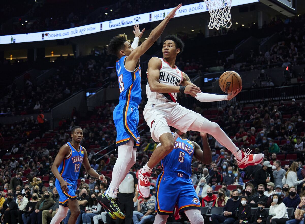 Portland Trail Blazers guard Anfernee Simons, right, looks to pass the ball as Oklahoma City Thunder guard Tre Mann defends during the first half of an NBA basketball game in Portland, Ore., Friday, Feb. 4, 2022. (AP Photo/Craig Mitchelldyer)