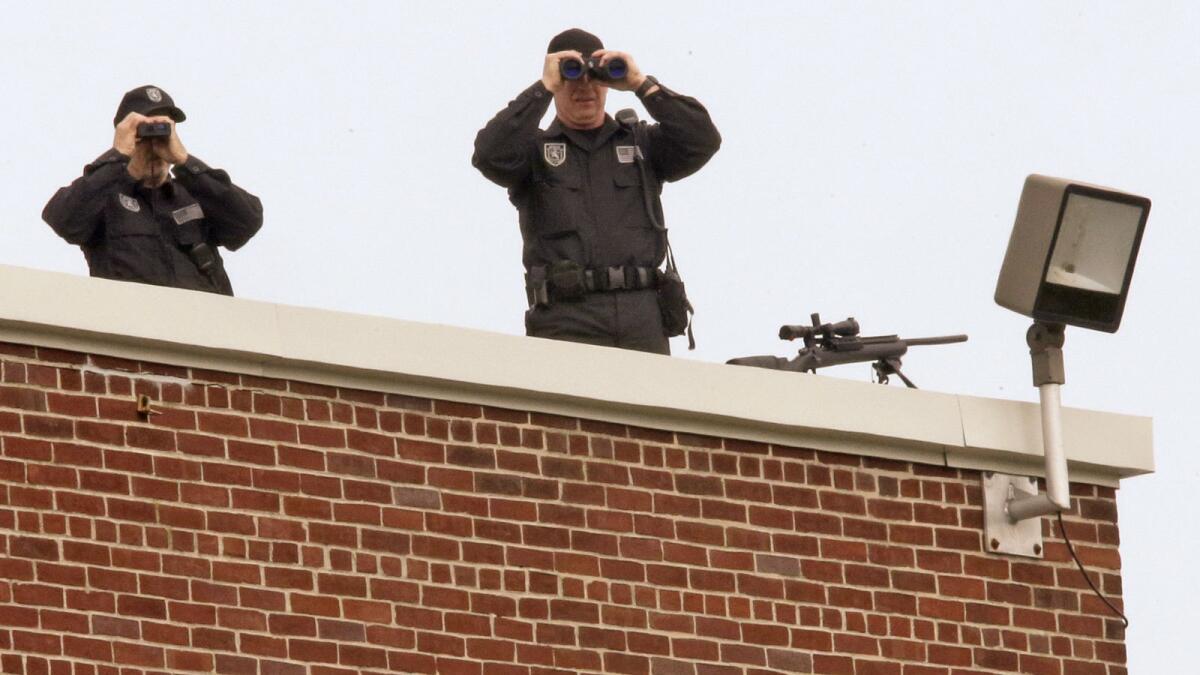Police snipers survey the area from the roof of an elementary school before the funeral Mass.