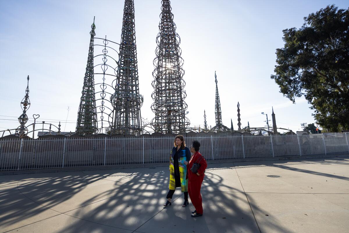 Two Black women — Elizabeth Alexander and Rosie Lee Hooks — walk through the elaborate shadows cast by the Watts Towers.