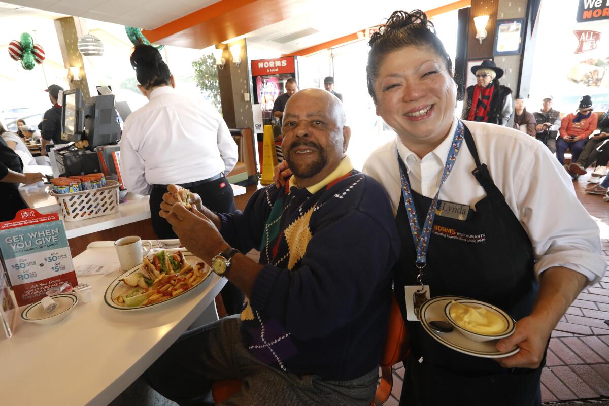 Amid the chaos of a post-Christmas December morning at Norms, customer Paul Welch and waitress Lynda Sato find a moment to share a smile for the camera.