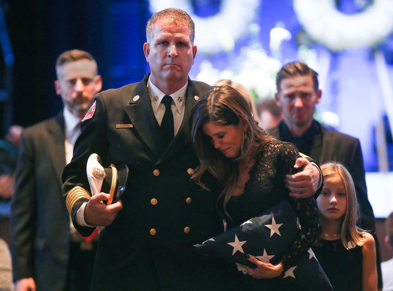 Costa Mesa Fire Chief Dan Stefano walks with Shanna Kreza during memorial service for her husband Costa Mesa Fire Capt. Michael Kreza, at the Saddleback Church in Lake Forest on Friday.