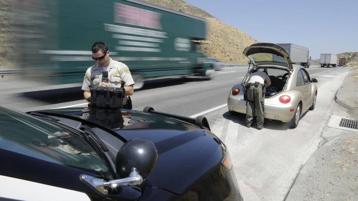 Los Angeles County Sheriff's deputies from a anti-trafficking team search a vehicle on the 5 Freeway in July. A Times' analysis of the team's stops found Latino drivers are stopped and searched far more often than other races.
