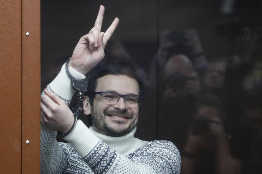 Russian opposition activist and former municipal deputy of the Krasnoselsky district Ilya Yashin gestures, smiling as he stands inside a glass cubicle in a courtroom, prior to a hearing in Moscow, Russia, Friday, Dec. 9, 2022. Yashin faces a trial on charges stemming from his criticism of the Kremlin's action in Ukraine. (Yury Kochetkov/Pool Photo via AP)