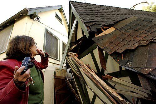 Hollywoodland Realty owner Patricia Carroll inspects her garage after it was crushed by a 170-foot-tall pine that toppled in a windstorm. The tree just missed the distinctive Hansel-and-Gretel realty office, which was built in 1923 as a home sales office by the developer of Hollywoodland. The Hollywood sign was erected to advertise the Hollywoodland subdivision.