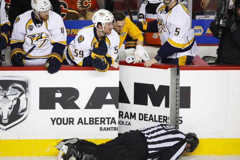 Nashville Predators look over the bench at linesman Don Henderson after he was hit by Flames defenseman Dennis Wideman during the second period of a game on Jan. 27.