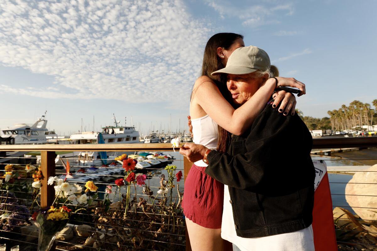 Olivia, left, sister of a female crew member who died in the boat fire, hugs Jennifer Stafford, who placed flowers at a memorial at the Santa Barbara Harbor.