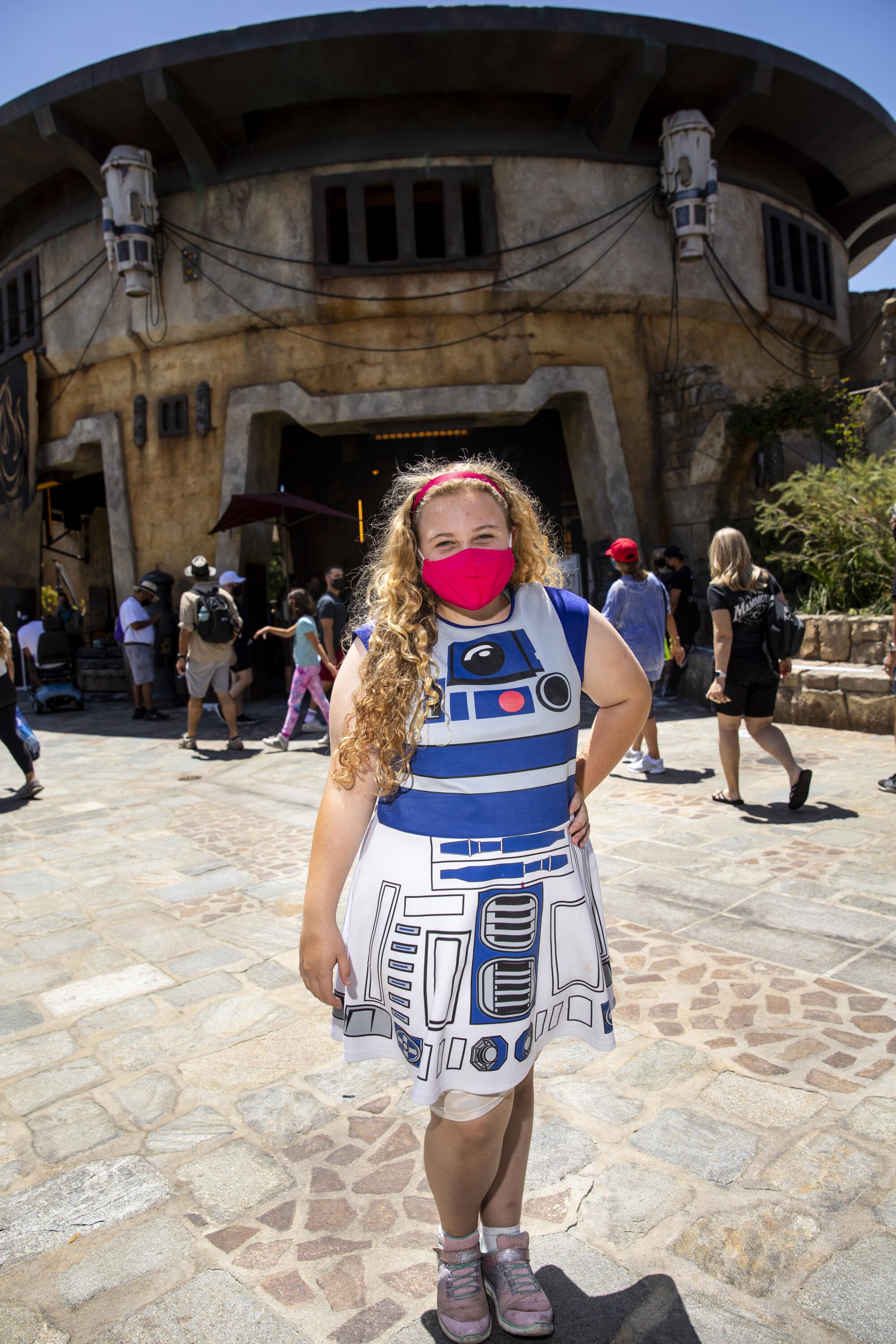 A woman wears a dress with an R2-D2 design.