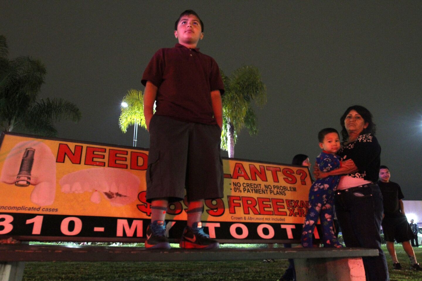 Jose Salgado, 9, watches from Central Avenue as Los Angeles County sheriff's officials investigate the scene in a Tam's Burgers parking lot, where two men were struck in a hit-and-run involving music mogul Suge Knight.