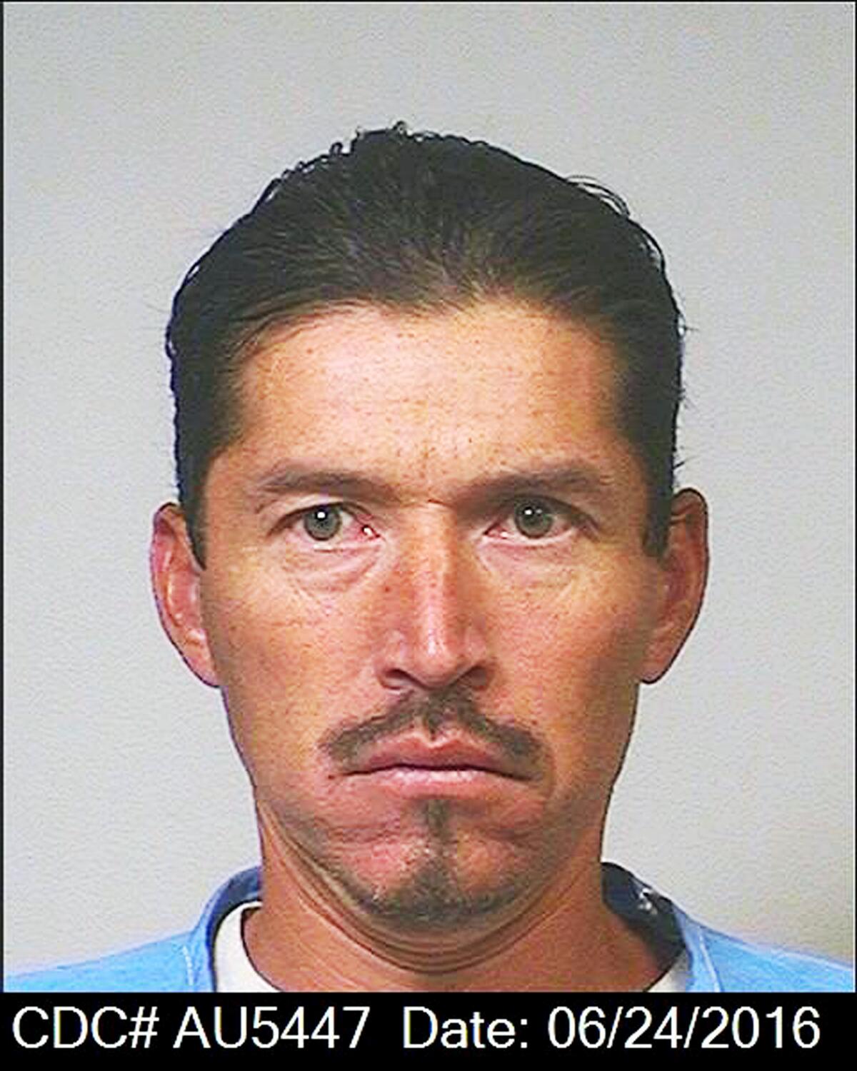 A prison booking mugshot of a man with facial hair