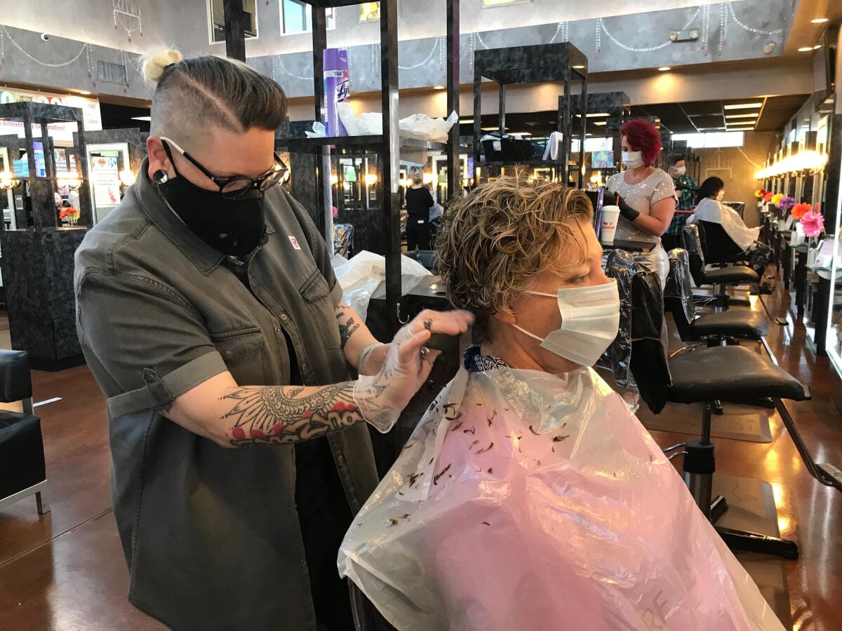 Natascha Updegrove, a stylist at Three-13 Salon, Spa and Boutique, cuts Karon Gilmore's hair on the first day that Georgia reopened salons, spas, gyms and bowling alleys.