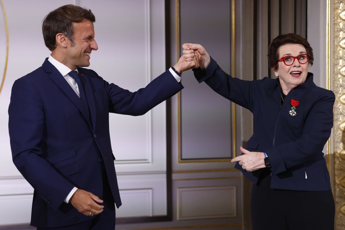 French President Emmanuel Macron holds the hand of tennis legend Billie Jean King, of the U.S, after she was awarded with the Legion d'Honneur at the Elysee Palace Friday, June 3, 2022 in Paris. A ceremony Thursday at the Roland Garros stadium marked the 50th anniversary of her French Open win.(AP Photo/Jean-Francois Badias, Pool)