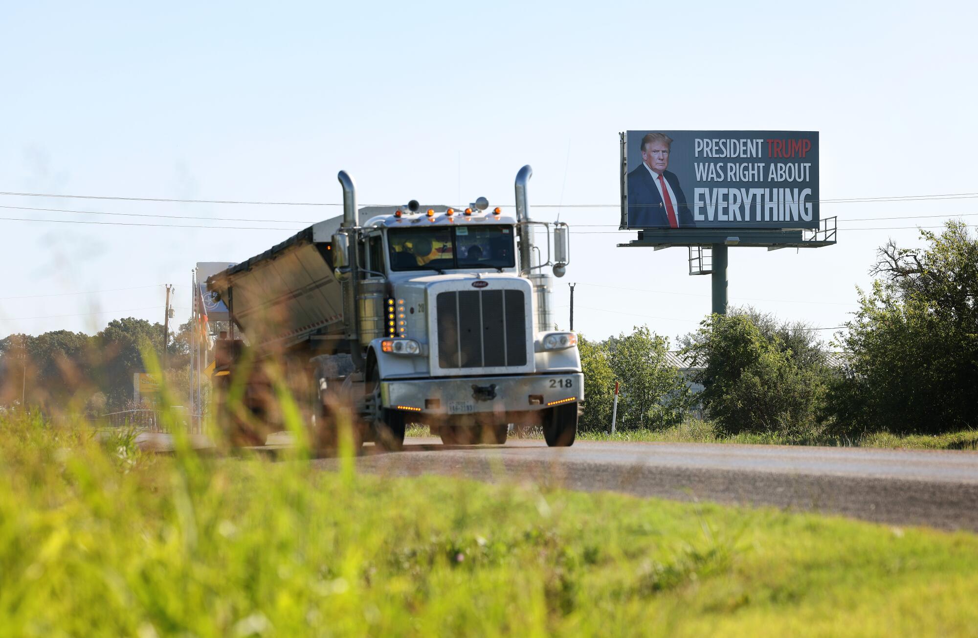 A commercial truck passes by a President Trump billboard  