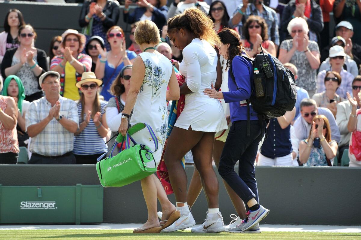 Serena Williams leaves the court with medical personnel after retiring from a women's doubles match Tuesday.
