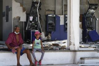 Residents sit at a bank lacking windows and with destroyed bank teller machines two days after the passage of Hurricane Otis as a Category 5 storm in Acapulco, Mexico Friday, Oct. 27, 2023. (AP Photo/Marco Ugarte)