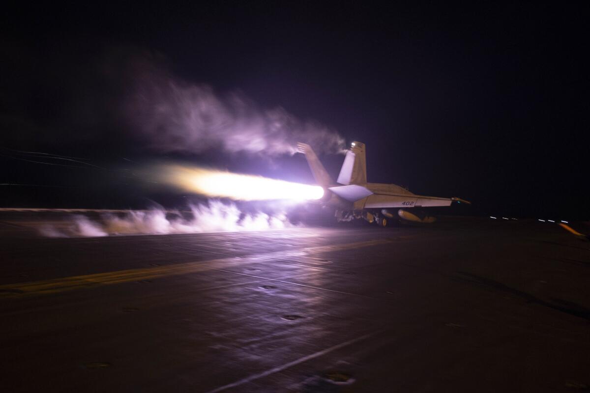 A fighter jet taking off from an aircraft carrier in the dark