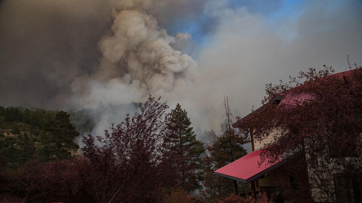 A house is covered in pink fire retardant as the Cranston Fire burns out of control near the town of Idyllwild.