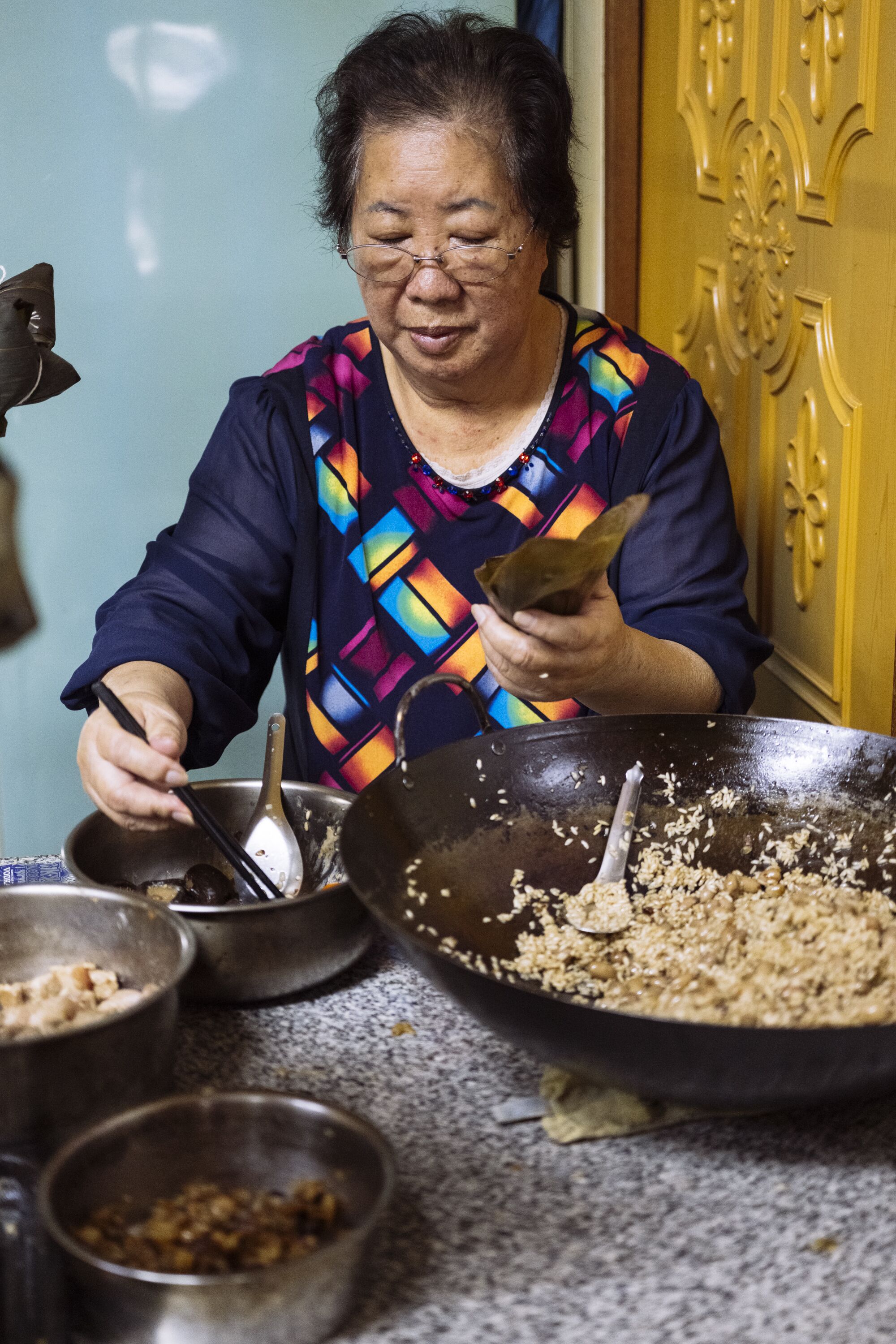 A woman uses chopsticks to make zongzi