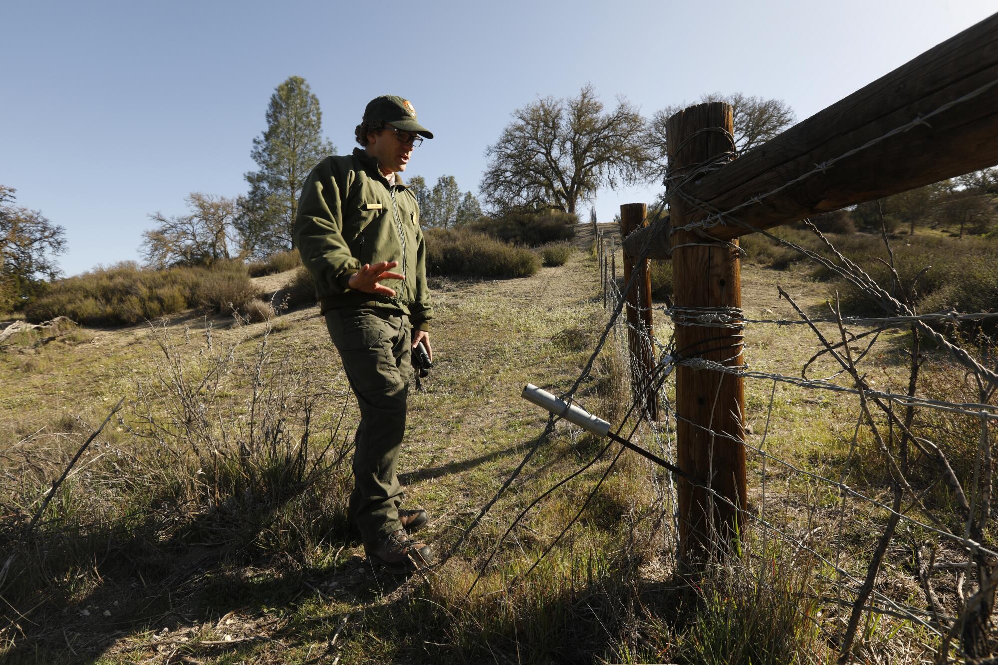 A man stands by a fence