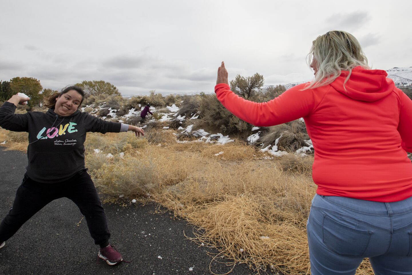 Pacoima residents Andrea Hernandez, right, lifts a hand to deflect a snowball about to be thrown by friend Maria Salazar, left, as desert snow lingers in the Antelope Valley town of Palmdale in Palmdale, Calif., on Dec. 1, 2019.