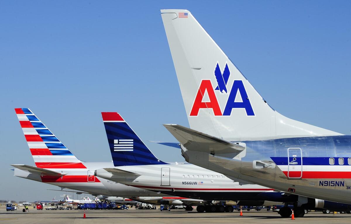 American Airlines and US Airways planes wait at a terminal at the Dallas/Fort Worth airport in 2013. The FAA has approved a single operating certificate for a merged carrier.