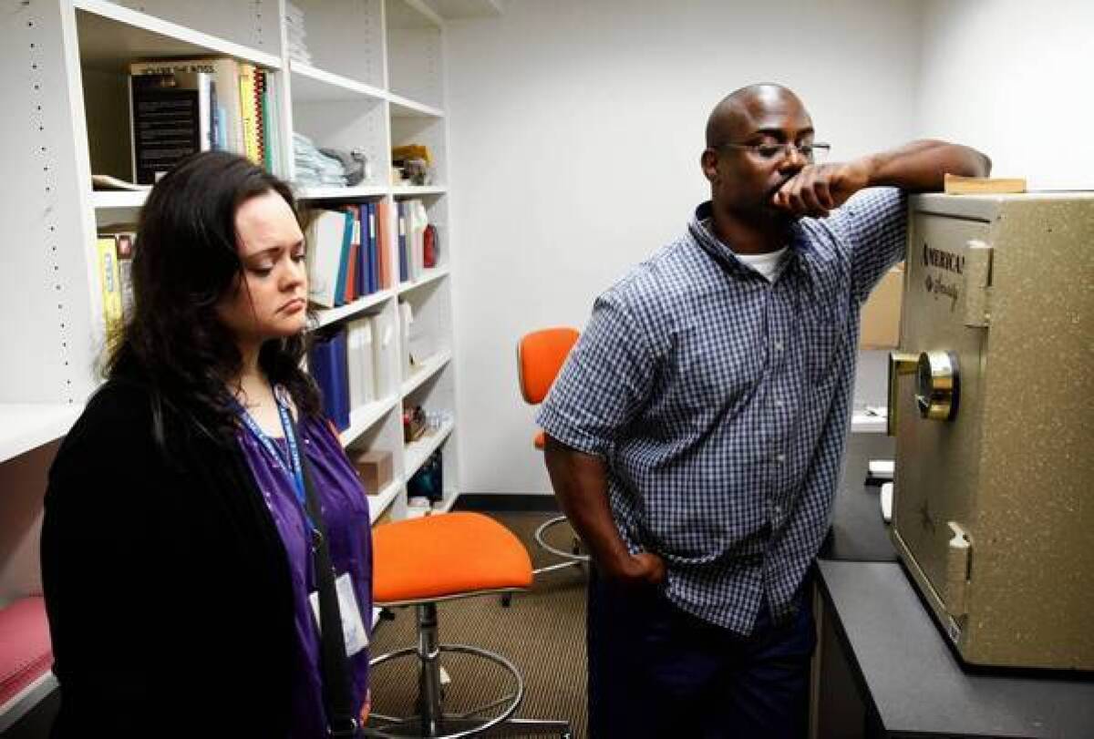 Santa Monica College lead library assistant Jan Juliani and computer support specialist Myron Kabwe revisit the storage room where they herded seven others to hide from a gunman, who shot into the room.