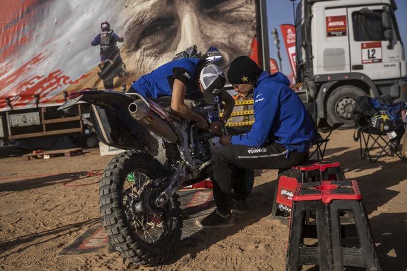 In this Monday, Jan. 13, 2020 photo, Sara Garcia of Spain checks her Yamaha motorbike, next to his partner Javier Vega of Spain at the Dakar rally "park ferme" in Wadi Al Dawasir, Saudi Arabia. Formerly known as the Paris-Dakar Rally, the race was created by Thierry Sabine after he got lost in the Libyan desert in 1977. Until 2008, the rallies raced across Africa, but threats in Mauritania led organizers to cancel that year's event and move it to South America. It has now shifted to Saudi Arabia. The race started on Jan. 5 with 560 drivers and co-drivers, some on motorbikes, others in cars or in trucks. Only 41 are taking part in the Original category. (AP Photo/Bernat Armangue)