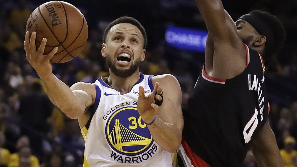 Golden State Warriors' Stephen Curry, left, lays up a shot past Portland Trail Blazers' Maurice Harkless during the first half of Game 1 of the Western Conference finals on Tuesday in Oakland.